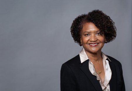 Portrait of Dr. Elaine Batchlor, a middle aged Black woman, in front of gray backdrop